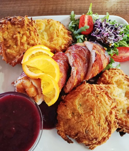 Baconbe tekert, aszalt szilvával töltött, göngyölt csirkemellfilé, narancsos áfonya mártással és rösztivel